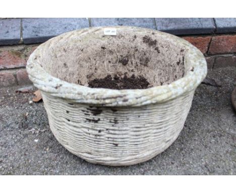A cast wicker basket effect circular garden planter 