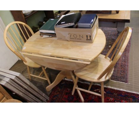 A modern blonde wood kitchenette suite comprising, circular topped twin flap table and two stick back solid seated chairs 