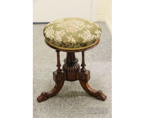 three legged carved detail piano stool with turned central support and tapestry covered seat