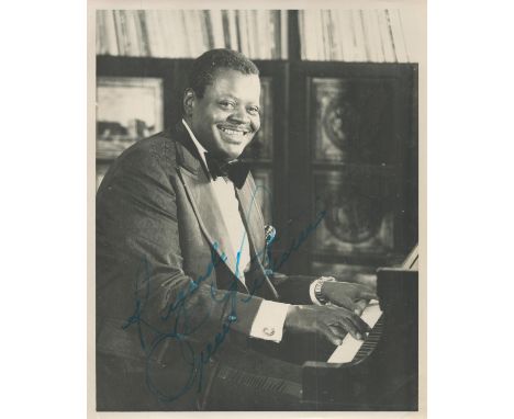 Music Oscar Peterson signed vintage 10 x 8 inch black and white photo. Sitting playing his piano. Signed in blue in to left h