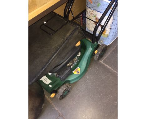 A petrol lawn mower with instructions manual and bottle of oil 