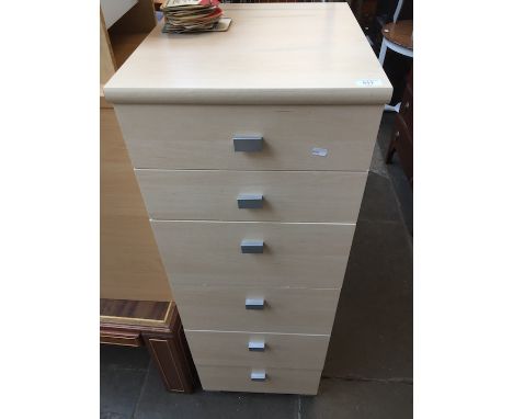 A narrow light wood effect chest of drawers. 