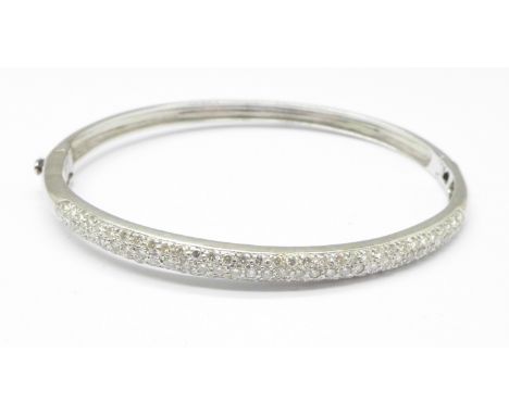 A white metal and diamond set bangle, marked 750, 14.2g