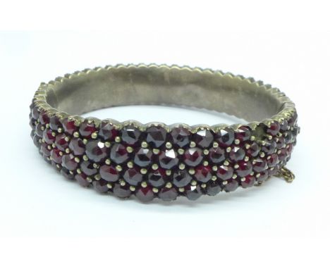 A Bohemian white metal and garnet bangle, lacking one stone