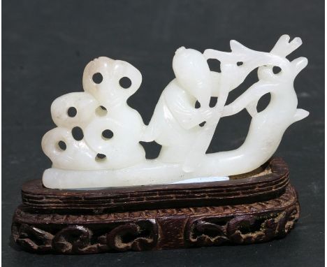 A Chinese jade carving depicting a figure in a boat, on a pierced hardwood stand, 8cms (3ins) long.Condition ReportMinor loss