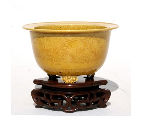 A Chinese yellow glazed three-legged planter with sgrafitto decoration depicting dragons amongst clouds chasing a flaming pea