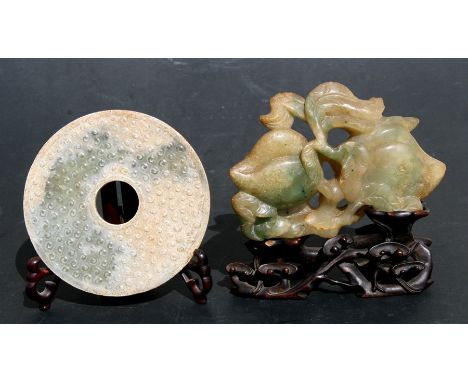 A Chinese jade or green hardstone carving depicting two peaches and foliage, on a carved hardwood stand, 13cms (5ins) high; t