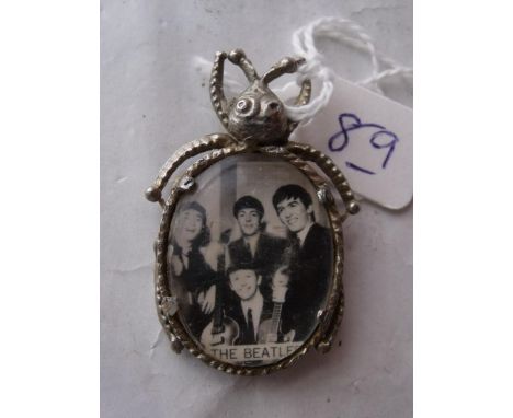 A VINTAGE METAL BEATLE BROOCH  containing a photograph of the pop group  'The Beatles'        