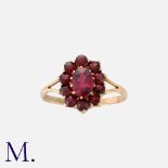 A Garnet Cluster Ring in 9k yellow gold, set with an oval garnet in a border of round cut garnets.
