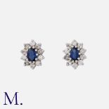 A Pair Of Sapphire And Diamond Cluster Earrings in white gold, each comprising an oval shaped blue