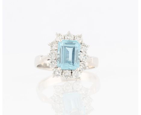 An aquamarine and diamond cluster ring, set with an emerald cut aquamarine, measuring approx. 8x6mm, surrounded by a border o