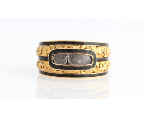 An early 19th Century memorial ring, set with a plaited hair panel covered with glass (A/F), with three rows of black enamel 