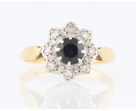 A sapphire and diamond flower cluster ring, set with a central round cut sapphire, surrounded by a border of eight eight-cut 