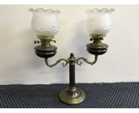 A two branch brass oil lamp with glass shades, height 60cm.