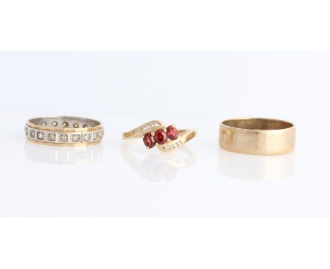 A garnet and diamond ring, stamped 375, a hallmarked 9ct yellow gold wedding band and full paste eternity ring, (3).