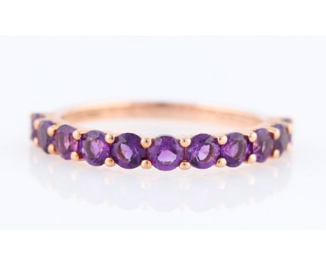 *An amethyst half eternity ring, set with eleven round cut amethysts, rose metal stamped 375/1000, ring size P½.
