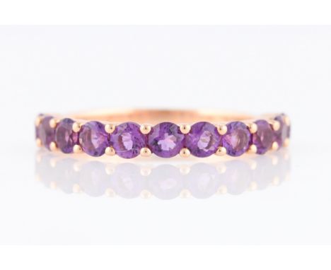 *An amethyst half eternity ring, set with eleven round cut amethysts, rose metal stamped 375/1000, ring size M.