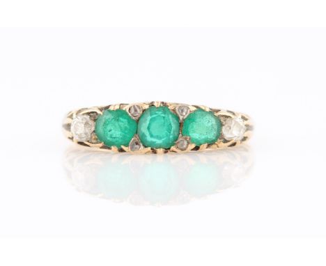 An emerald and diamond five stone ring, set with three central graduated round cut emeralds, flanked to either side with two 