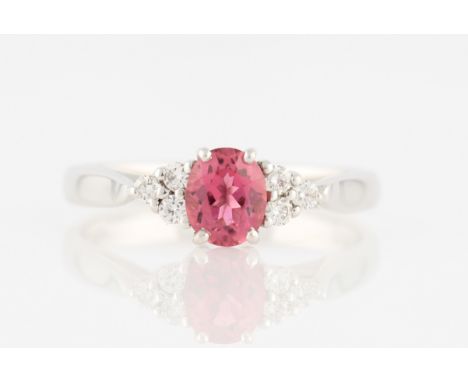 An 18ct white gold pink tourmaline and diamond ring, set with a central oval cut pink tourmaline, measuring approx. 6x5mm, fl