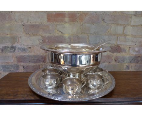A large modern plated punch bowl on stand with ladle and seven cups 