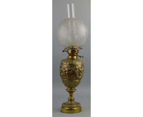 A brass table oil lamp, of urn shaped form cast with a band of cherubs engaged in various pursuits between acanthus leaf and 