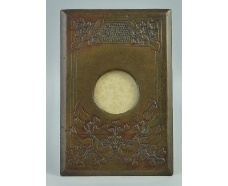 A leather covered easel photograph frame, of oblong form with central circular aperture, 6.5cm diameter and Arts & Crafts sty