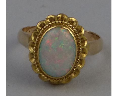 An opal ring, comprising an oval opal panel in a pierced setting on 18ct gold shank, stamped 18k, size N