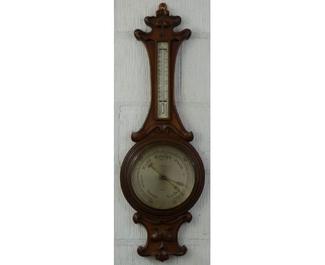 An early 20th Century oak cased aneroid barometer, the Art Nouveau style carved and pierced top over a thermometer with silve