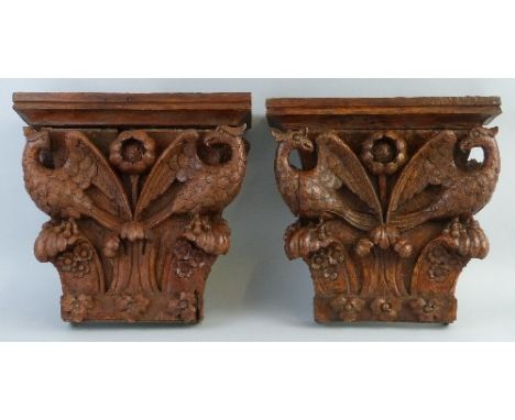 A matched pair of architectural wooden capitals, each carved in high relief with a central flowerhead flanked by two phoenix 