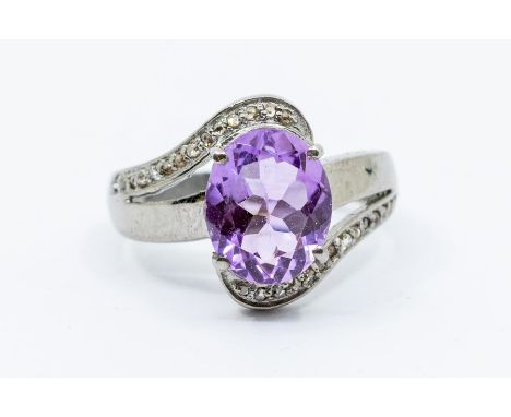 An amethyst and diamond silver dress ring, comprising a claw set oval cut amethyst set to the centre,  approx 8 x 10mm, withi