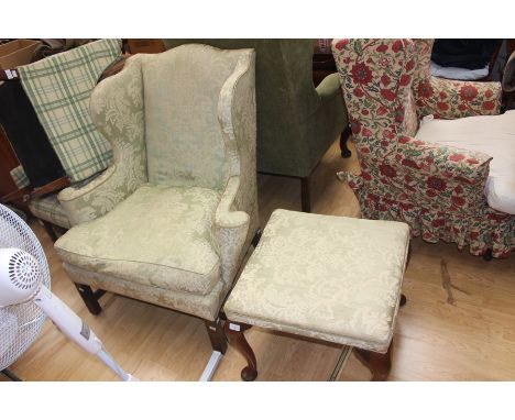 A George III style wing back armchair, green floral patterned upholstery, raised on square supports, measuring 102cm high, 98