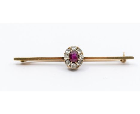 An Edwardian  ruby and diamond set 15ct gold bar brooch, comprising a central claw set oval ruby within a border of rose cut 
