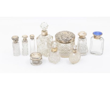 A collection of early 20th Century silver topped scent and toilet cut glass bottles, six with silver covers and collars, one 