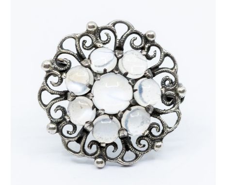 A silver and moonstone brooch by Bernard Instone, circular form claw set to the centre with a cluster of round cabochon moons