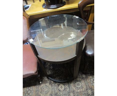 A c.1950 OCCASIONAL TABLE of circular outline with glazed top raised on moulded legs