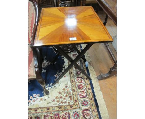 A FOLDING TABLE with segmented top raised on ebonised folding stand