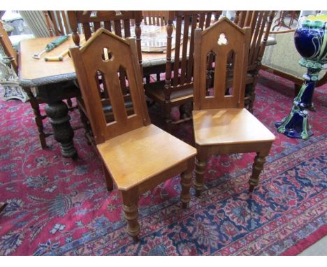 A pair of Victorian Arts &amp; Crafts oak hall chairs with cathedral arch back rest on turned and tapering legs, 101cm tall