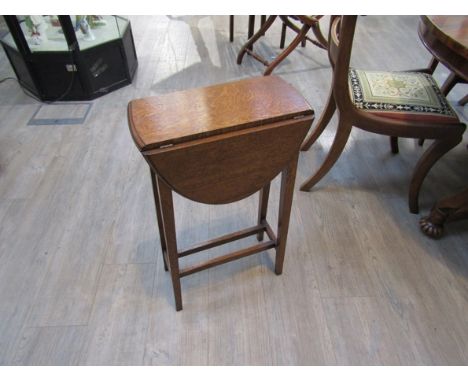 An Edwardian oak drop-flap revolving top occasional/lamp table on square tapering legs joined by a double H stretcher, 69cm t