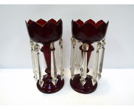 A pair of ruby glass Victorian lustres with castellated tops, hung with crystal droplets, damage present, 35cm tall  