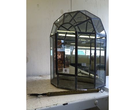 A glazed terrarium together with a brass fireside toasting fork.