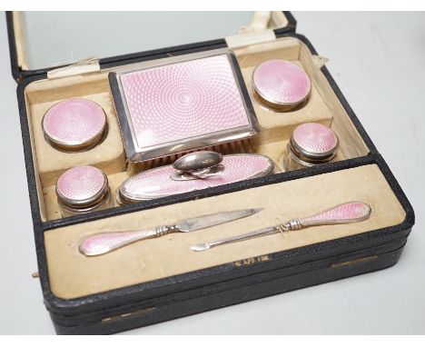 A cased George V nine piece silver and pink enamel mounted manicure set.