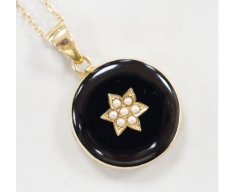 A late Victorian 15ct, black enamel and seed pearl set circular mourning locket, diameter 23mm, on a 9ct fine link chain, 40c