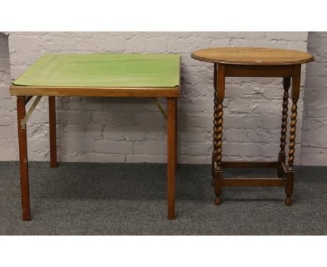 A light oak oval top occasional table raised on barleytwist supports, along with a folding games table.