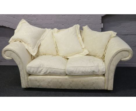 A cream upholstered scroll arm two seat sofa.