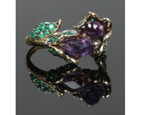 A 9ct gold floriform dress ring set with amethyst and having glass filled emerald shoulders, size N.