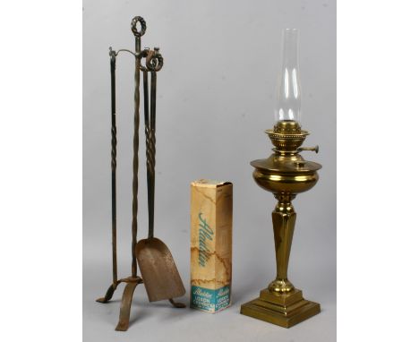 A Victorian brass based oil lamp and a wrought iron fire side companion set.