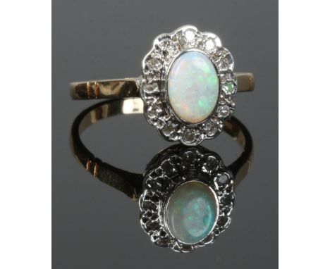 A 9ct gold ring set with an opal under a border of diamonds, assayed Birmingham 1985, size N.Condition report intended as a g