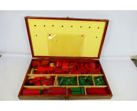 Meccano - A wooden storage case (suspected home made but good) containing an assortment of vintage Meccano pieces in green an