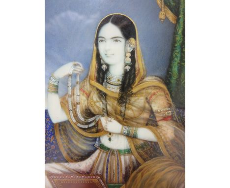 INDIAN SCHOOL, 19TH CENTURY. A portrait miniature depicting a young lady, seated, wearing intricate costume, on ivory, 3 1/2 