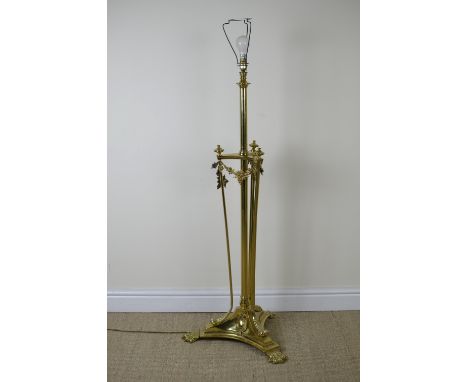 A brass Standard Lamp with turned central column and triple supports terminating in large paw feet